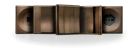 Ekinex ERA wall controls in a bronze-tone metal finish, shown as a row of switch plates and a socket